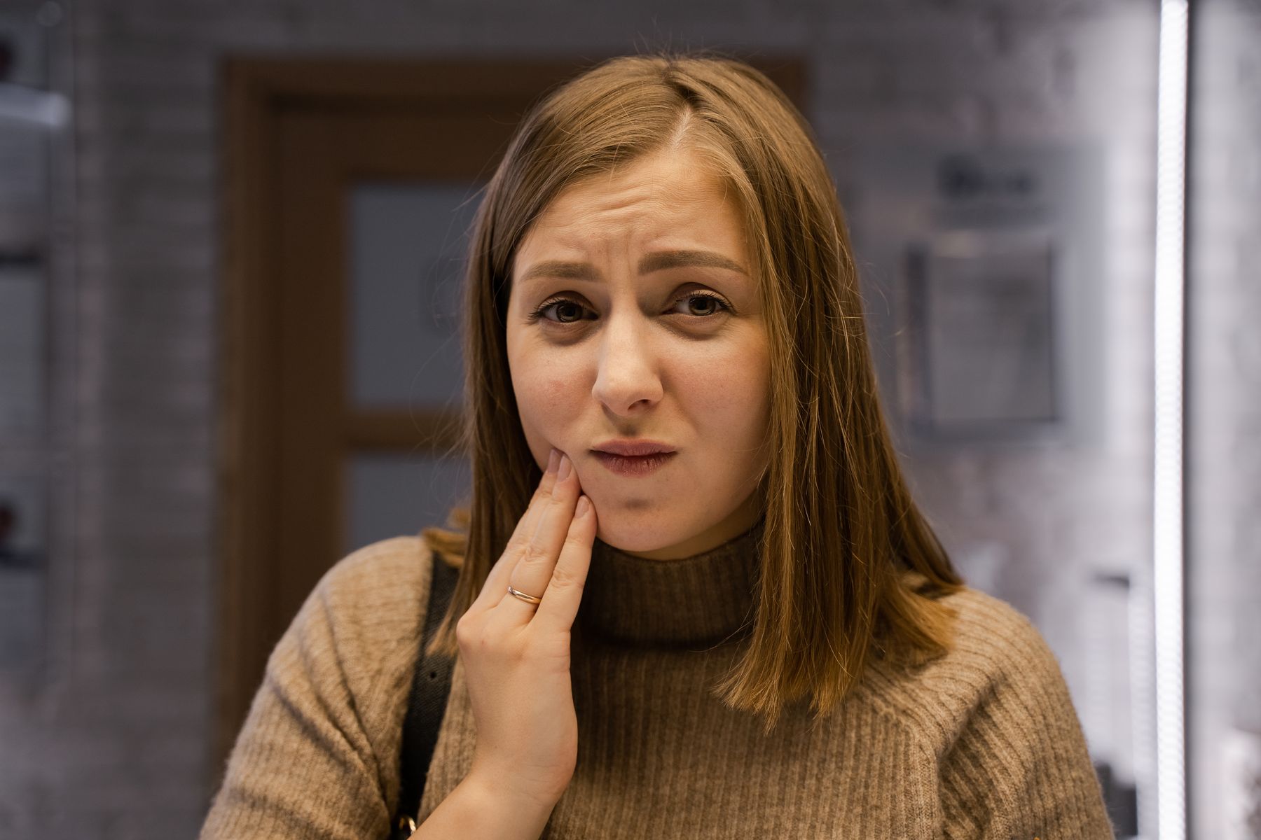 Woman touching her jaw while experiencing discomfort